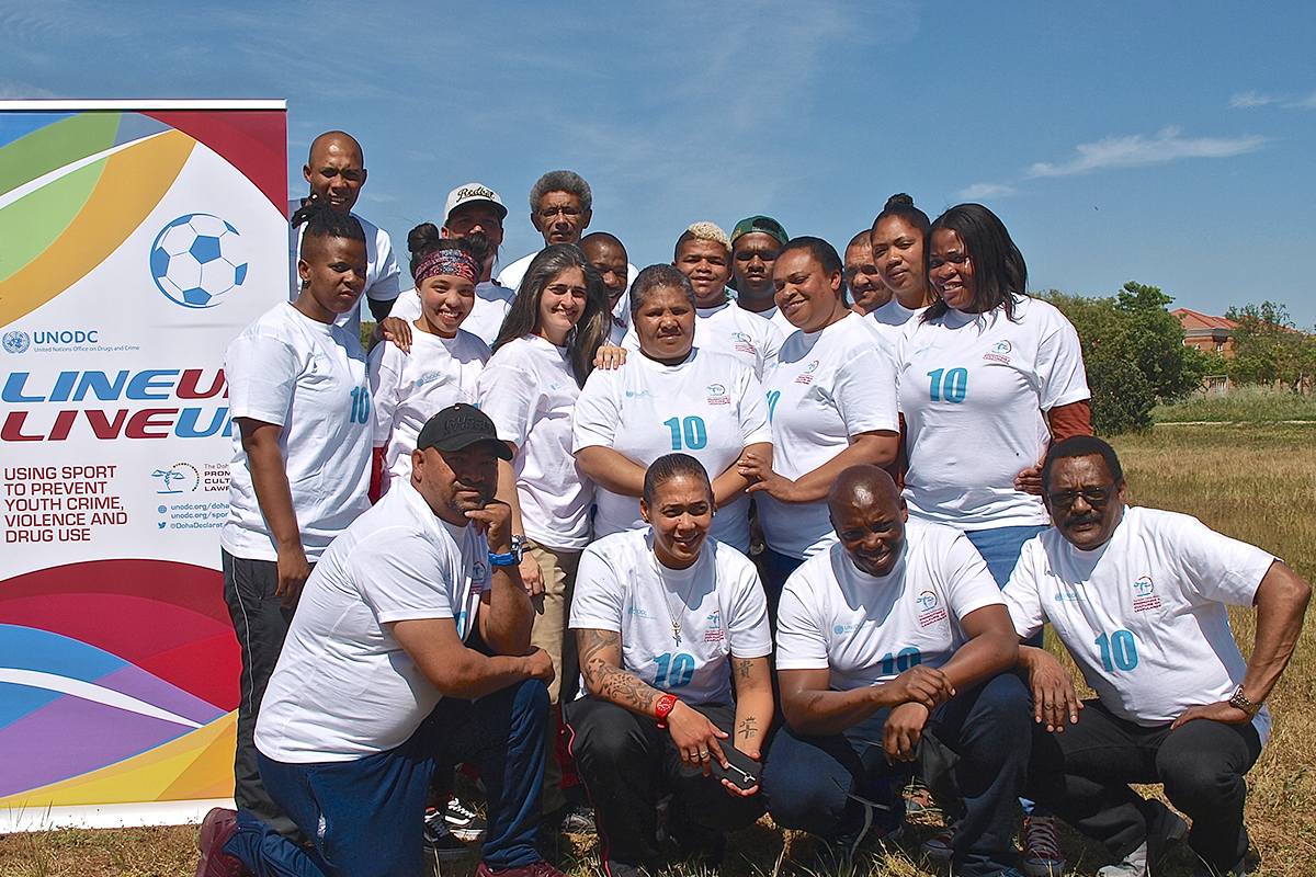 Civilian participants in a crime-prevention training programme stand beside a Line Up Live Up banner promoting sport to prevent youth crime, violence and drug use.