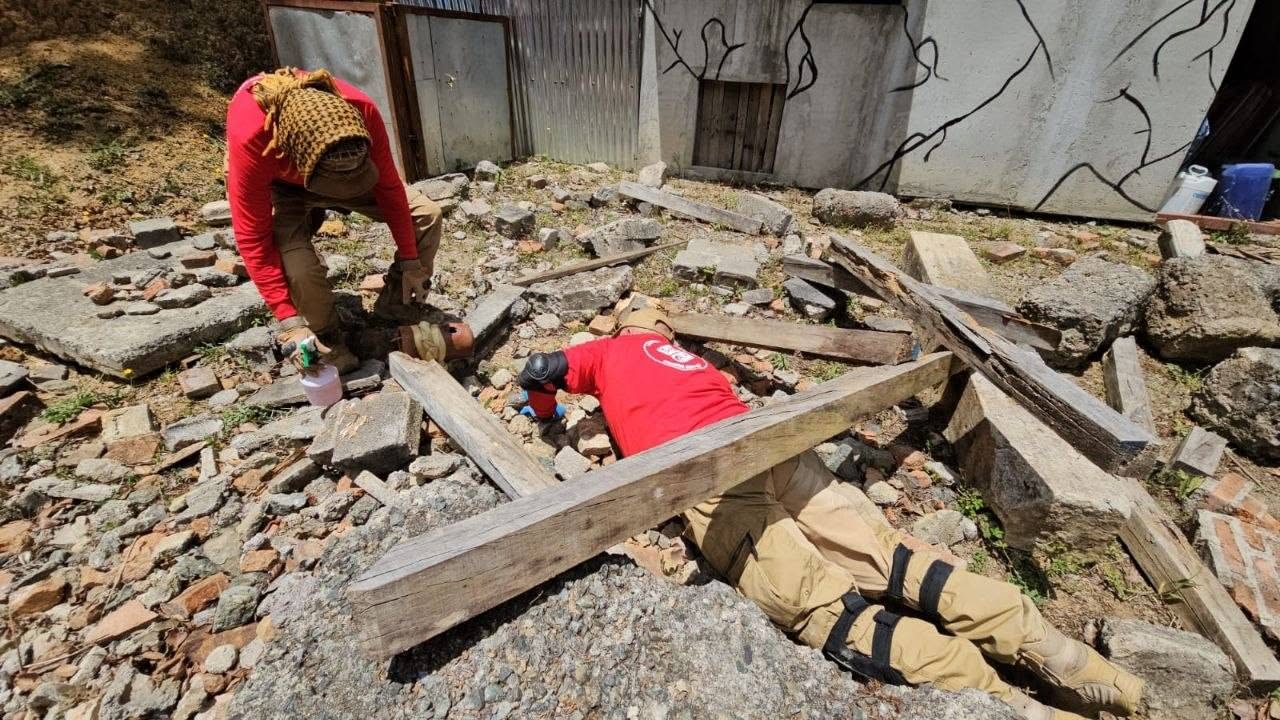 EEC responders in red shirts working among rubble and wooden beams.