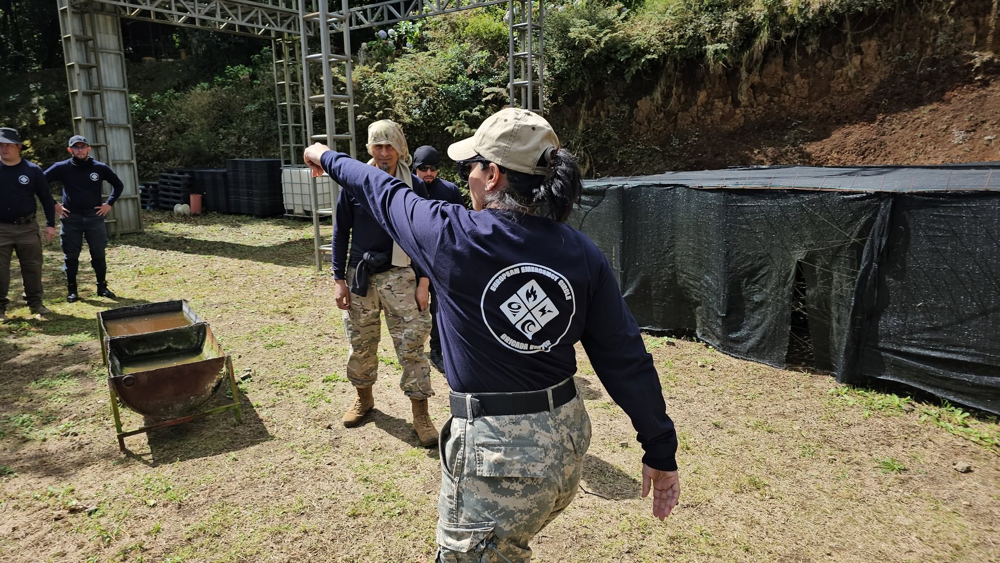 An EEC instructor in a navy shirt addresses colleagues during outdoor field training.