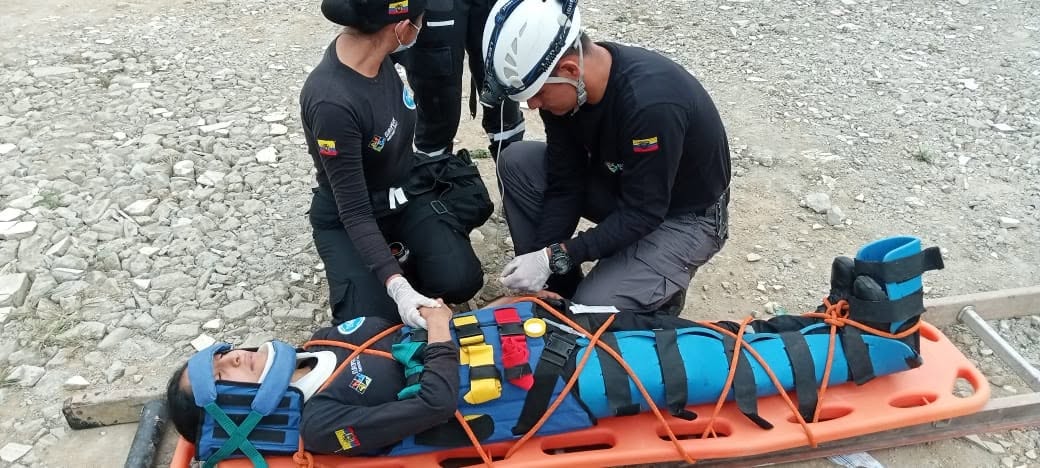 EEC rescuers secure a person with straps and ropes on an orange basket stretcher.