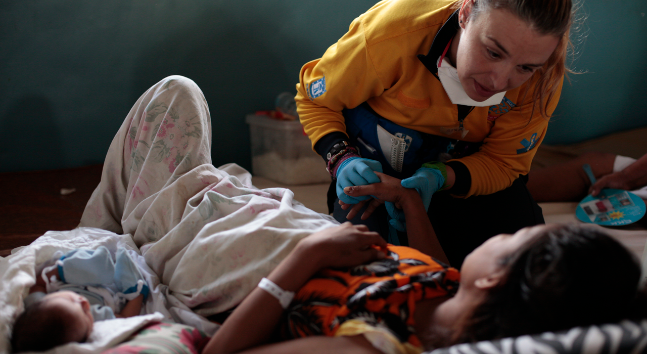 An emergency medical team member provides care to a mother beside her newborn during the Typhoon Haiyan response, in a photograph published by the World Health Organization.